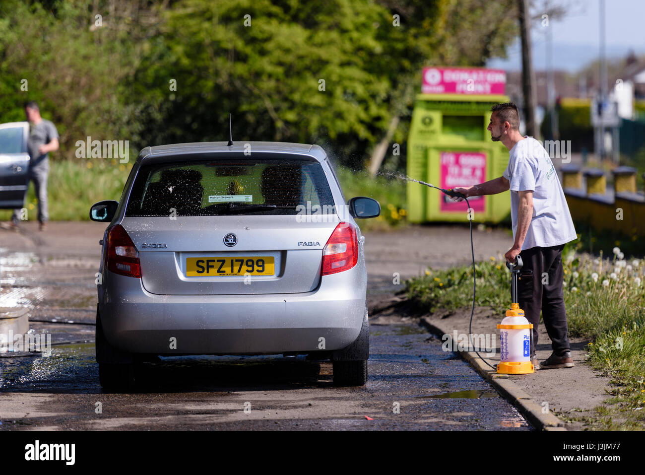 Un uomo rumeno lavaggi auto a un pop-up car wash. Foto Stock