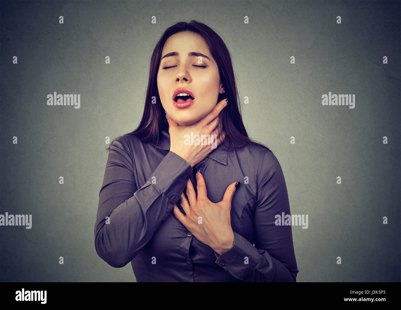 Giovane donna avente attacchi di asma o parzializzando non respiro che soffre di problemi respiratori isolati su sfondo grigio Foto Stock
