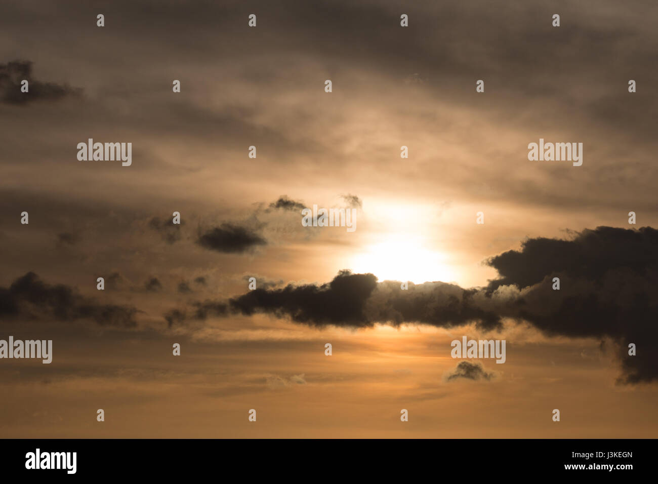 Sole che tramonta dietro le nuvole bello Foto Stock
