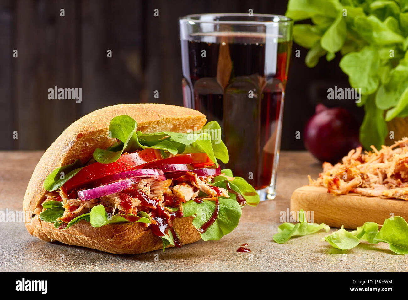 Sandwich con tirato la carne di maiale e il bicchiere di coca cola sul tavolo di pietra Foto Stock