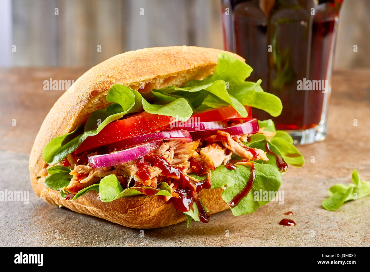 Sandwich con tirato la carne di maiale e il bicchiere di coca cola sul tavolo di pietra Foto Stock