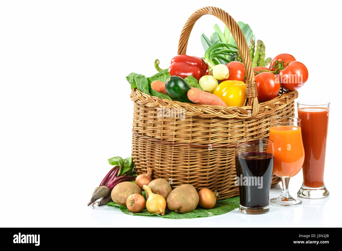 Mangiare sano concetto - cesto pieno di vari ortaggi e vari succhi di vegetali in bicchieri su sfondo bianco Foto Stock