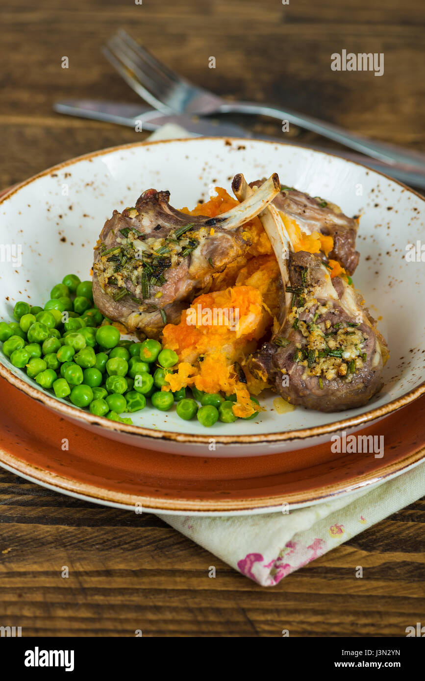 Il rosmarino costolette di agnello a cena con la carota e pastinaca mescolanza e piselli verdi Foto Stock