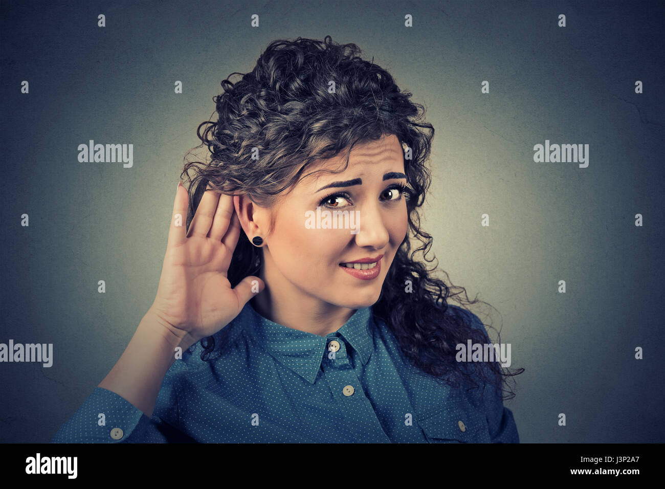 Closeup ritratto di scontento degli audiolesi donna mettendo mano sul orecchio chiedere a qualcuno di parlare o ascoltare la cattiva notizia isolata su sfondo grigio. Foto Stock