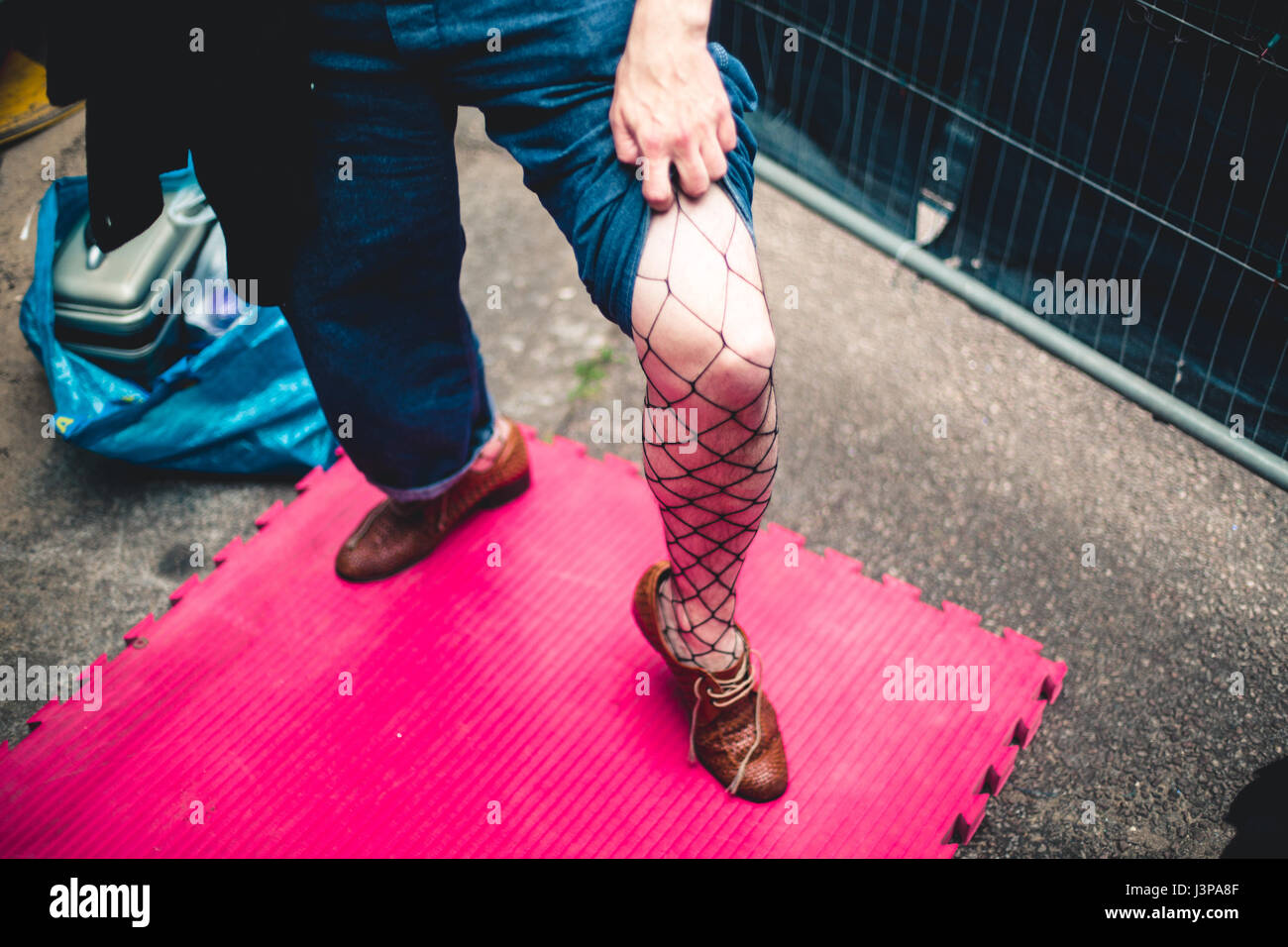 Un esecutore maschio può contenere fino i suoi jeans per mostrare i suoi collant sotto. Foto Stock