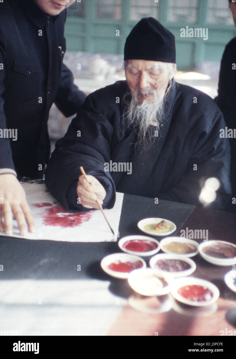 Qi Baishi pittura a scorrere nel suo studio a Pechino nel 1957, mesi prima di morire. Guardando sopra la sua spalla è suo figlio. Foto Stock