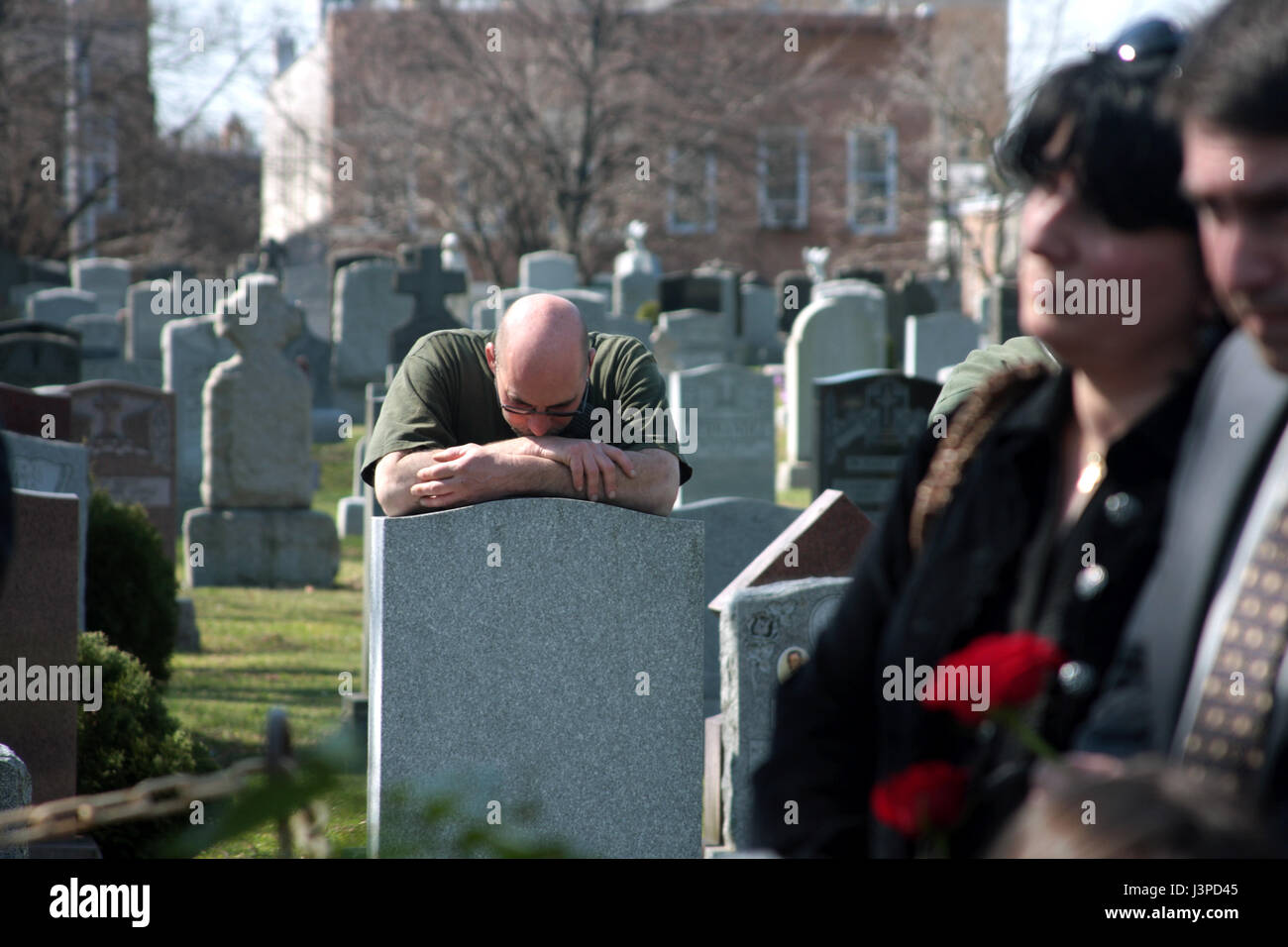 Uomo di piangere sulla lapide nel cimitero Foto Stock