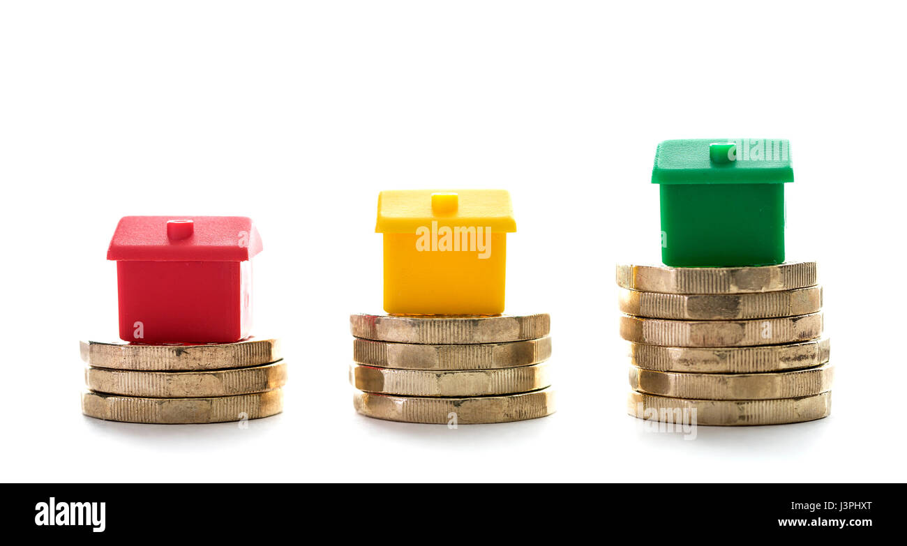 Tre case su palafitte di nuovo cancelletto monete su sfondo bianco Foto Stock