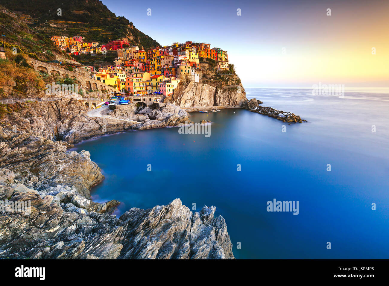 Manarola village sulla scogliera di rocce e mare al tramonto., Seascape in cinque terre, il Parco Nazionale delle Cinque Terre Liguria Italia Europa. Esposizione lunga Foto Stock