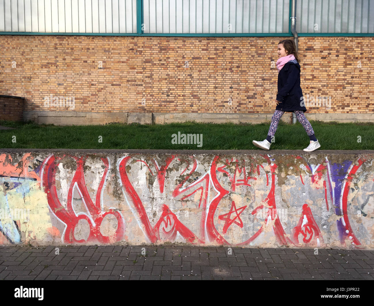 Berlino, Germania ragazza cammina su una parete dipinta con graffiti Foto Stock