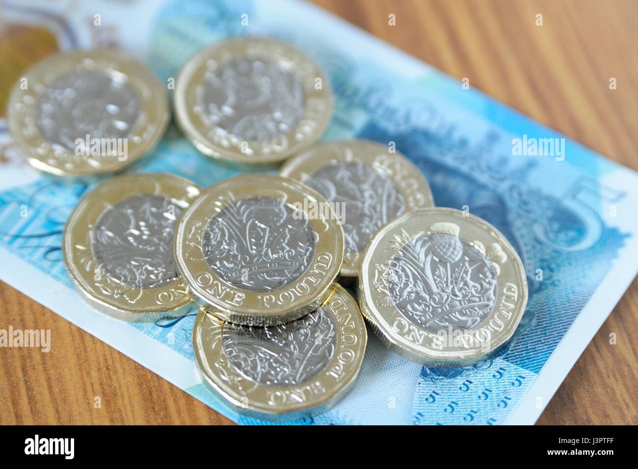 Nuovo cancelletto monete e cinque pound nota. Foto Stock