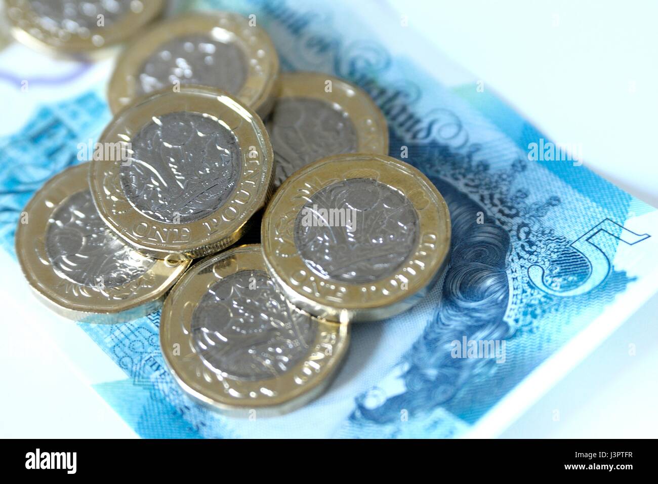 Nuovo cancelletto monete e cinque pound nota. Foto Stock