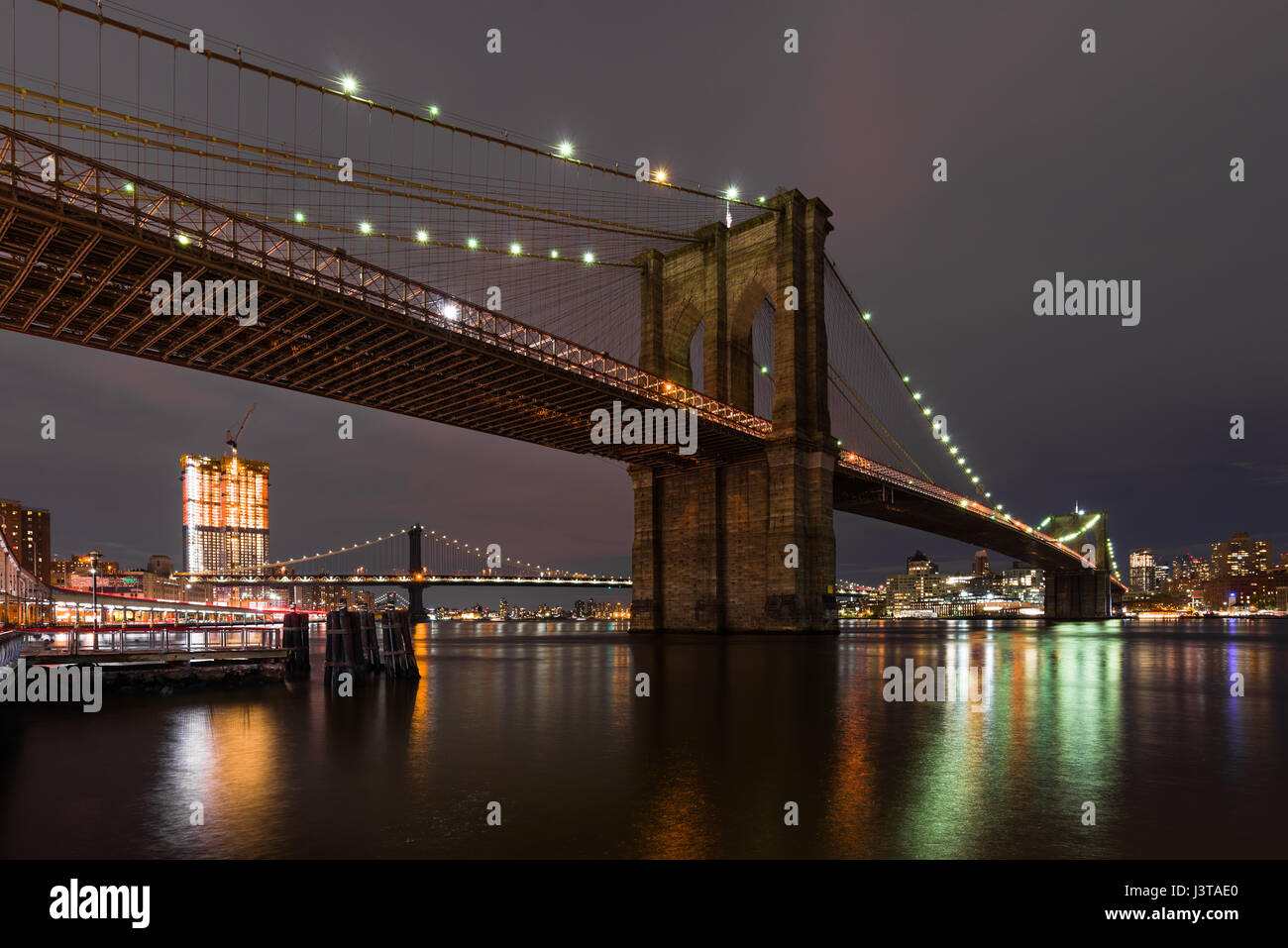 Il Ponte di Brooklyn al tramonto con le luci riflesse nell'East River, New York Foto Stock