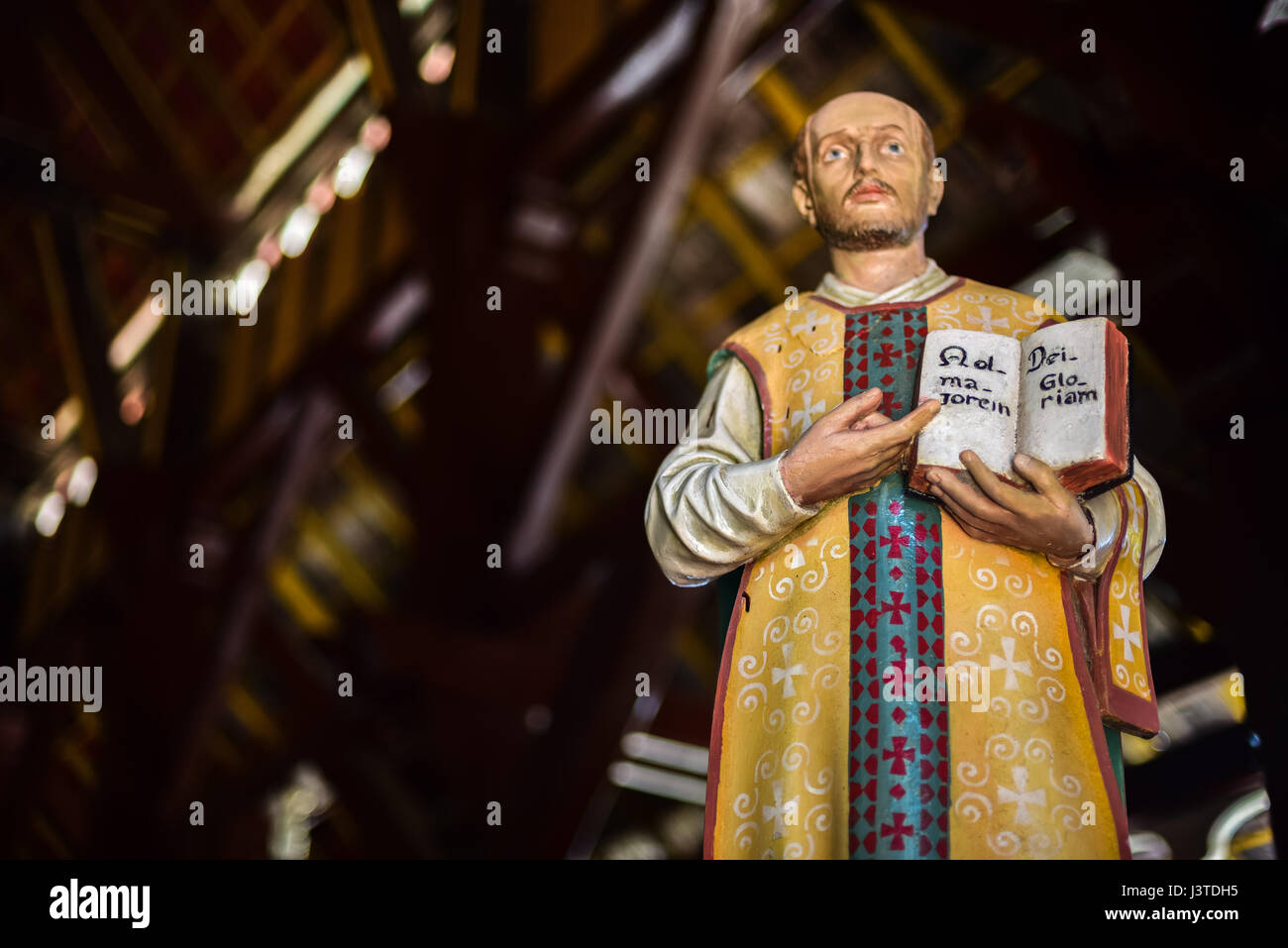 Statua di Sant'Ignazio di Loyola che mostra un libro con la frase latina scritta all'interno, alla chiesa di Sant'Ignazio Loyola a Sikka, Isola di Flores, Indonesia. Foto Stock