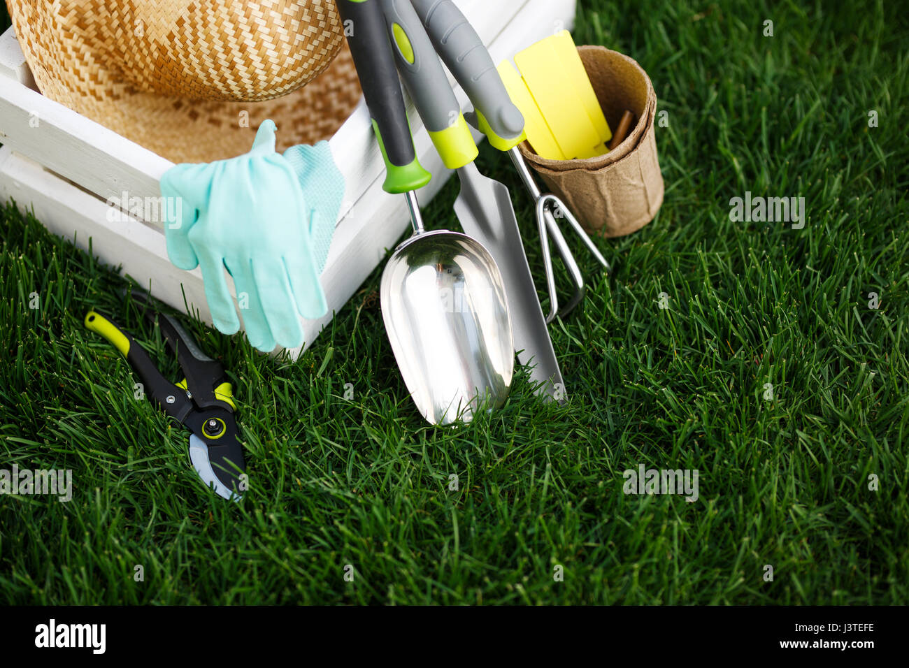 Utensili da giardinaggio e un cappello di paglia sull'erba nel giardino. Foto Stock