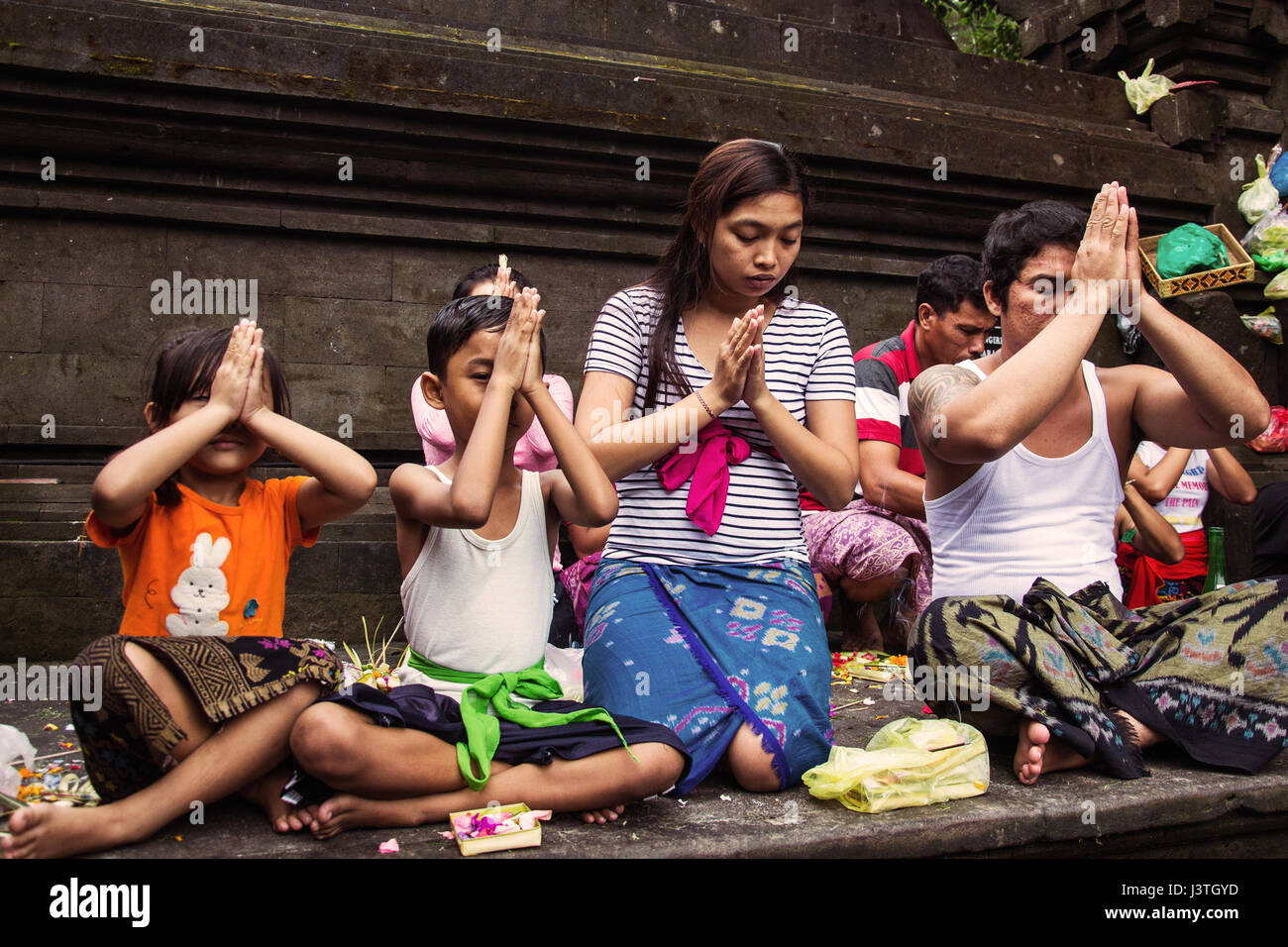 Famiglia indù pregano in un tempio di Bali Tirta Empul Foto Stock