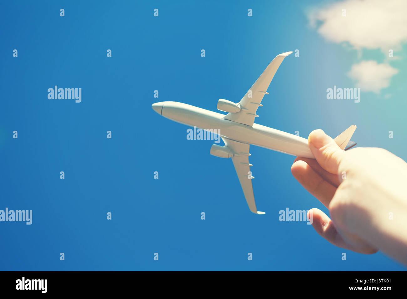 Sogni di viaggio - mano con un piccolo modello di aeroplano contro il cielo blu Foto Stock