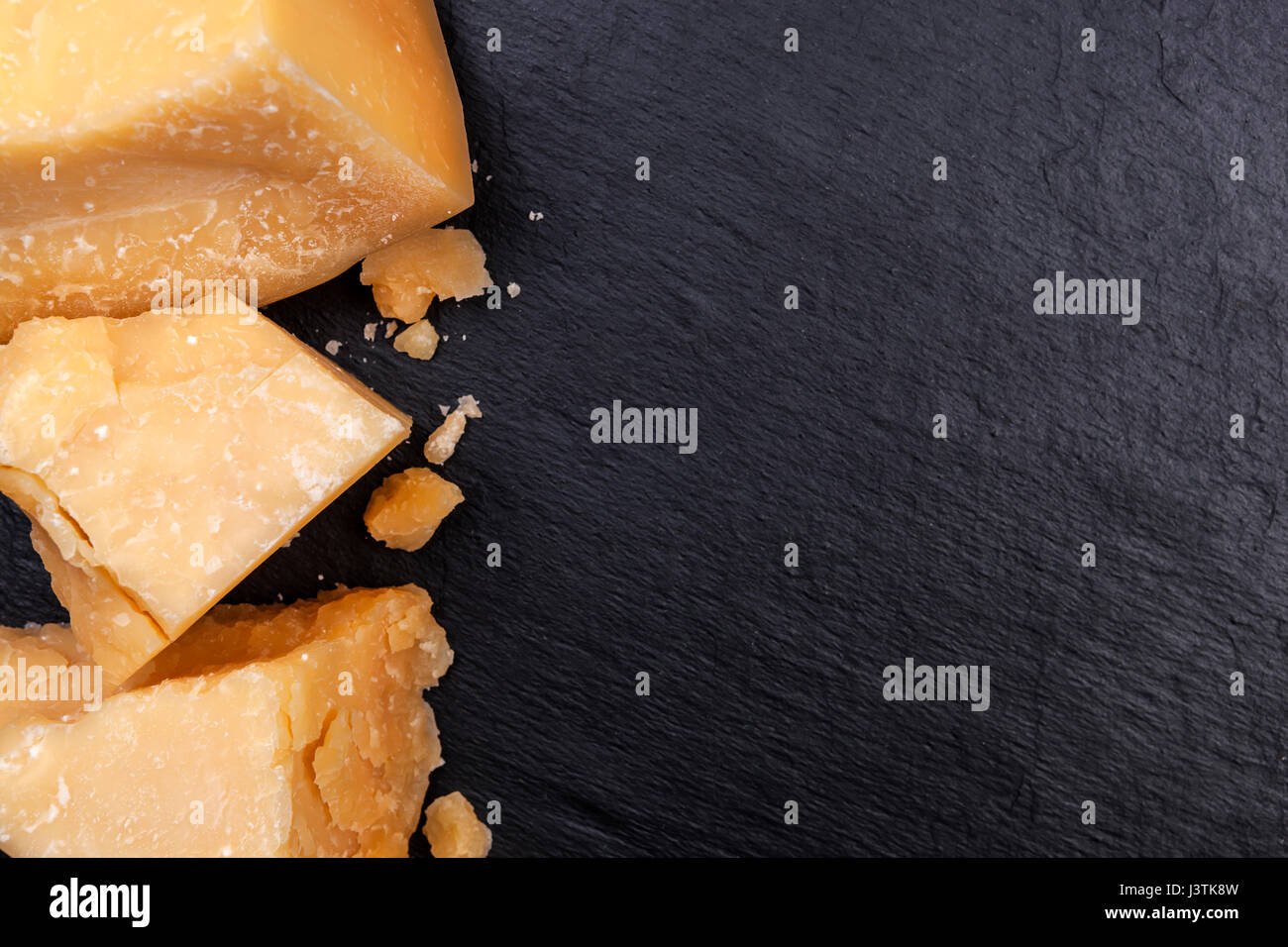 Formaggio parmigiano sulla pietra nera dello sfondo. Vista superiore, copia dello spazio. Foto Stock