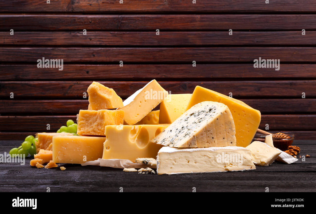Vari tipi di formaggio su tavoli in legno nero. Foto Stock