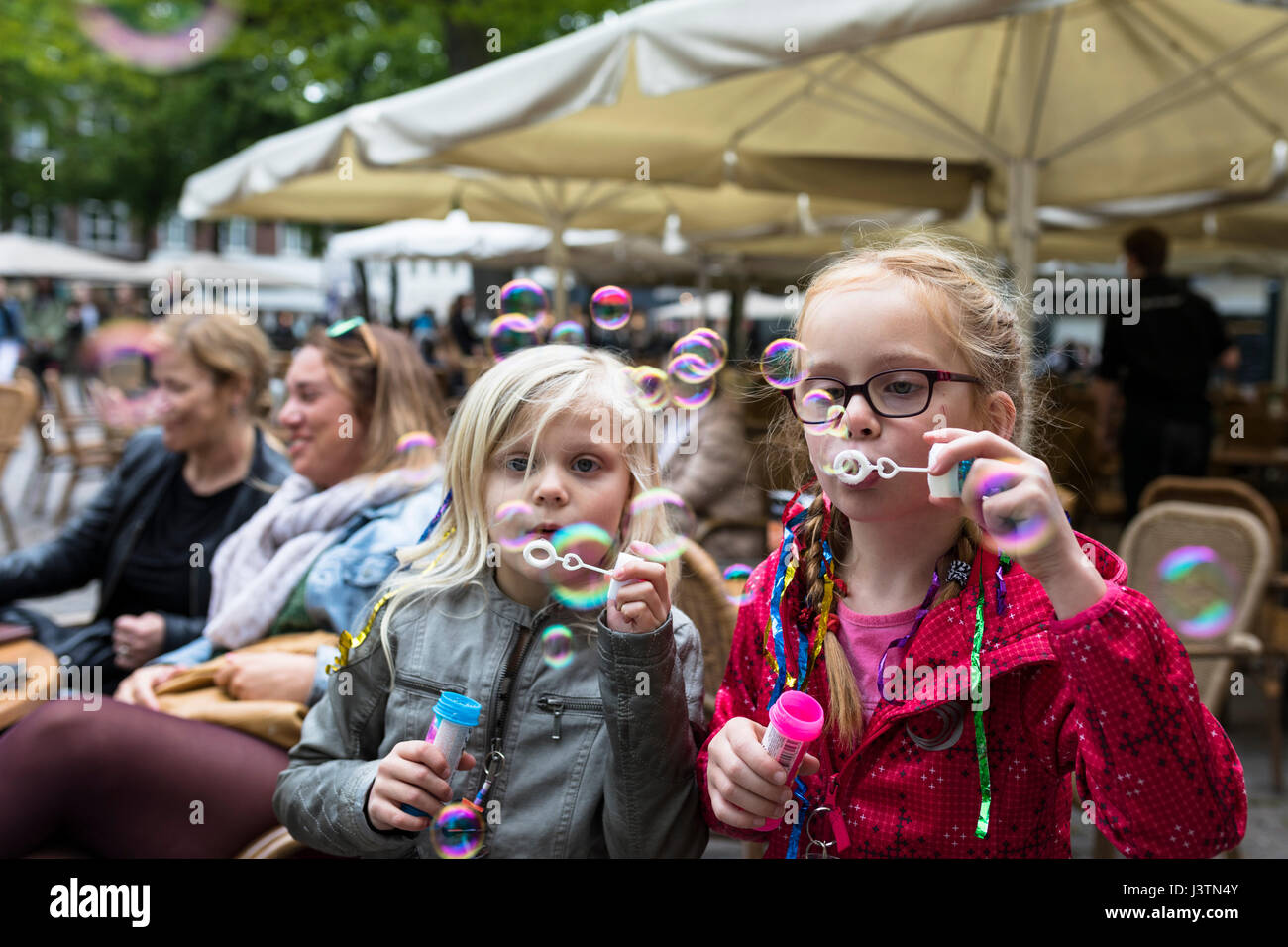Le giovani ragazze a soffiare bolle in corrispondenza di una terrazza, Paesi Bassi Foto Stock