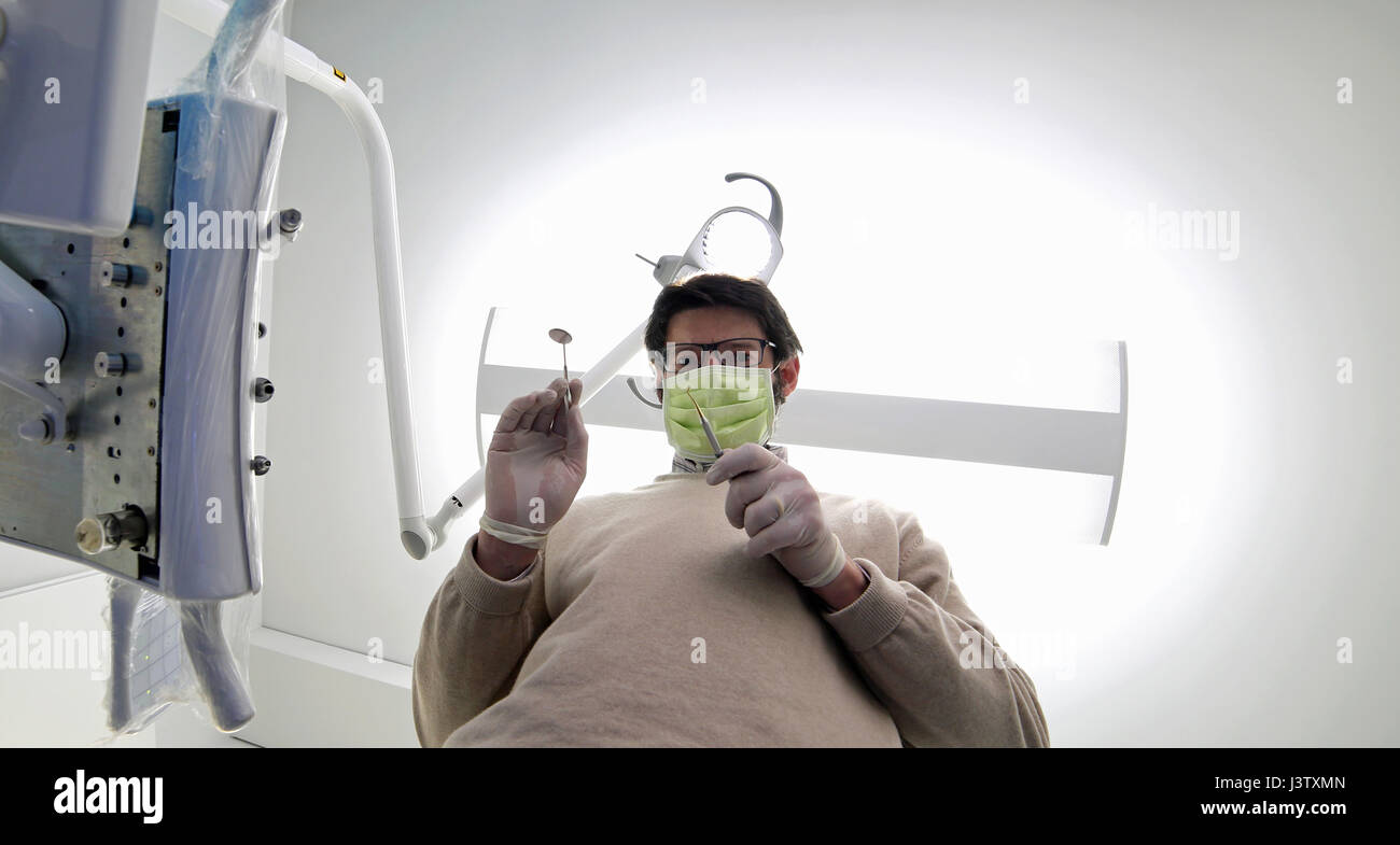 Uomo con maschera e strumenti bianco e guanti in lattice per la pulizia orale in uno studio dentistico Foto Stock
