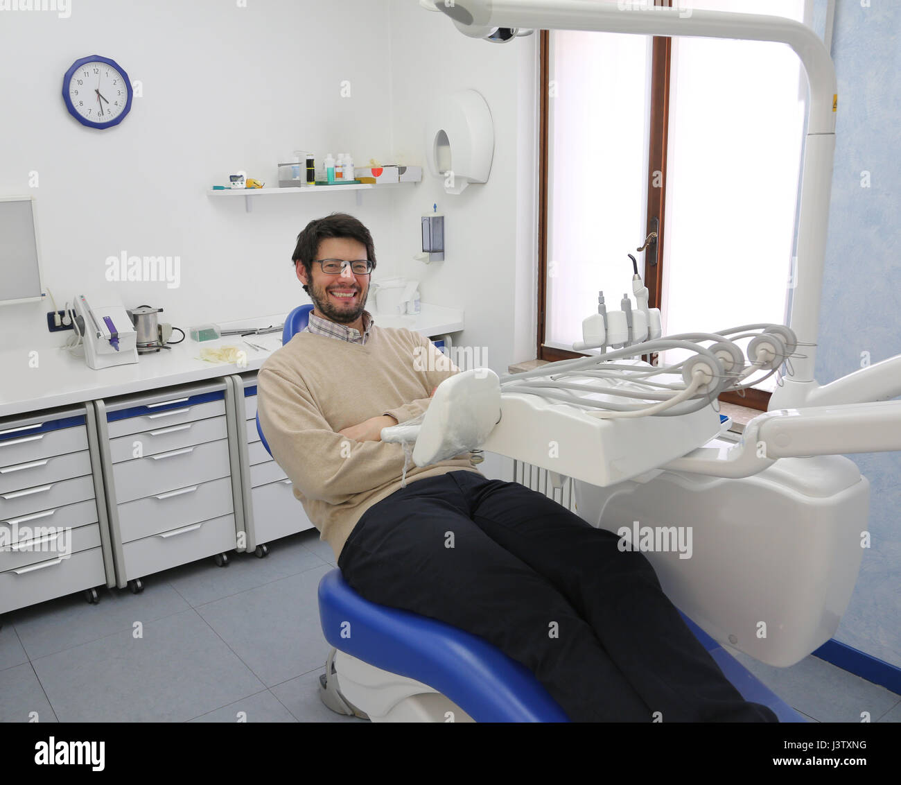 Uomo sorridente in attesa di dentista in chirurgia dentale Foto Stock