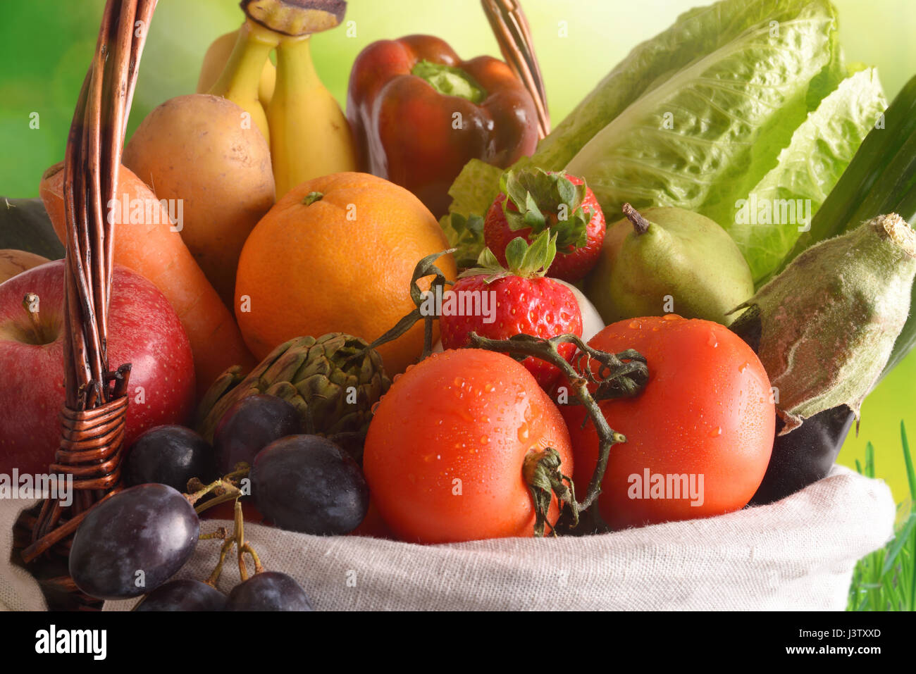 Assortimento di frutta e verdura in un cesto di vimini con sfondo verde.  Composizione orizzontale. Vista frontale Foto stock - Alamy