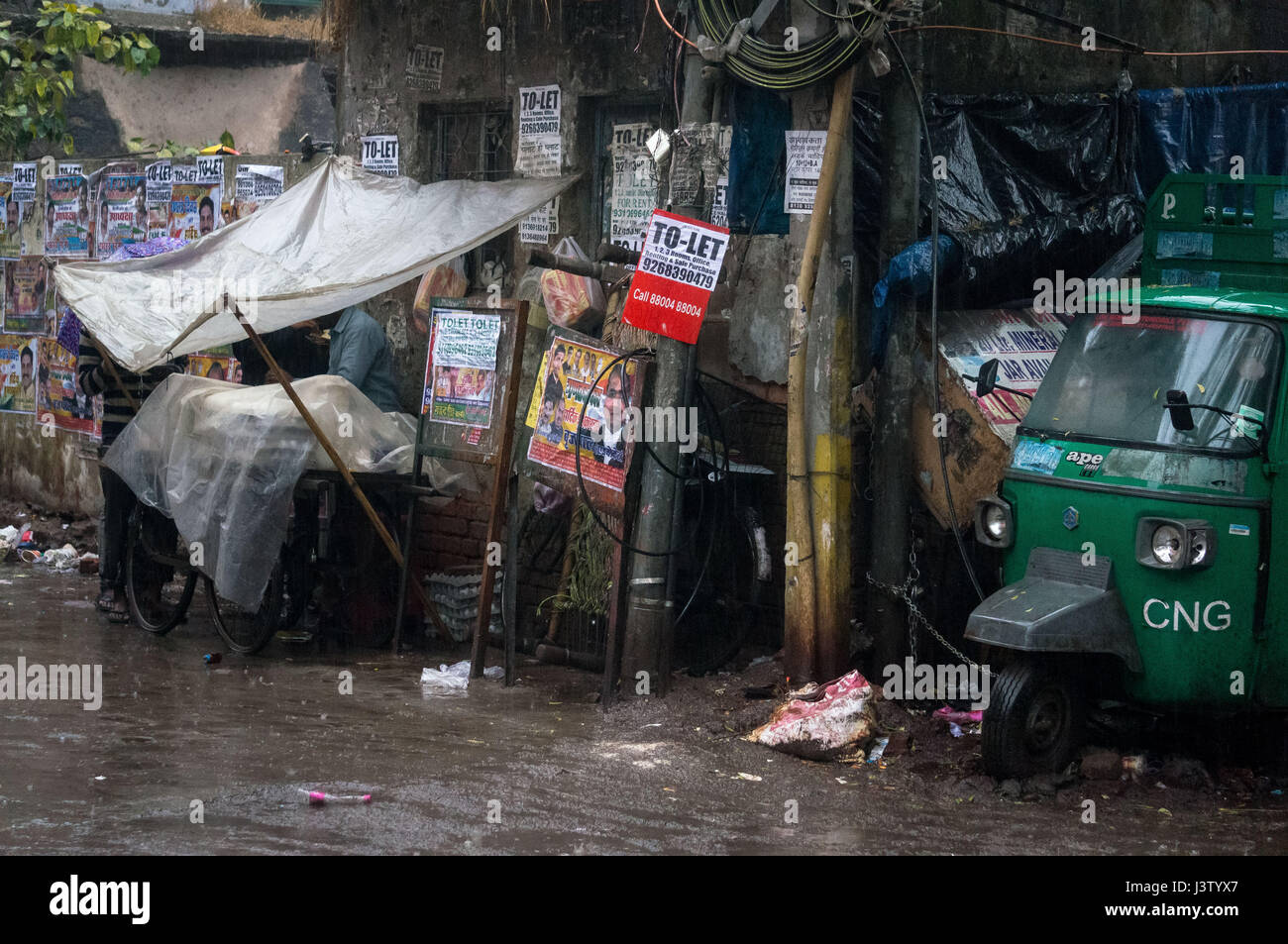 Pioggia bagna lungo una strada laterale a Delhi, India Foto Stock