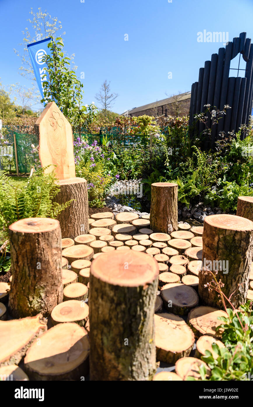 Patio sedie costruite da tronchi di legno disposti in un cerchio con pavimentazioni in legno in un giardino. Foto Stock