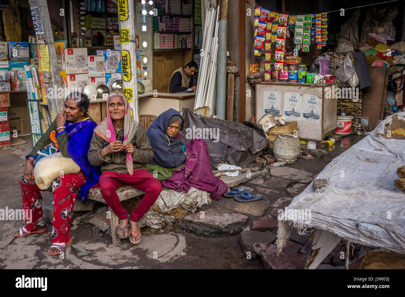 Tre signore a Delhi che un riposo nel mercato affollato (wide shot) Foto Stock