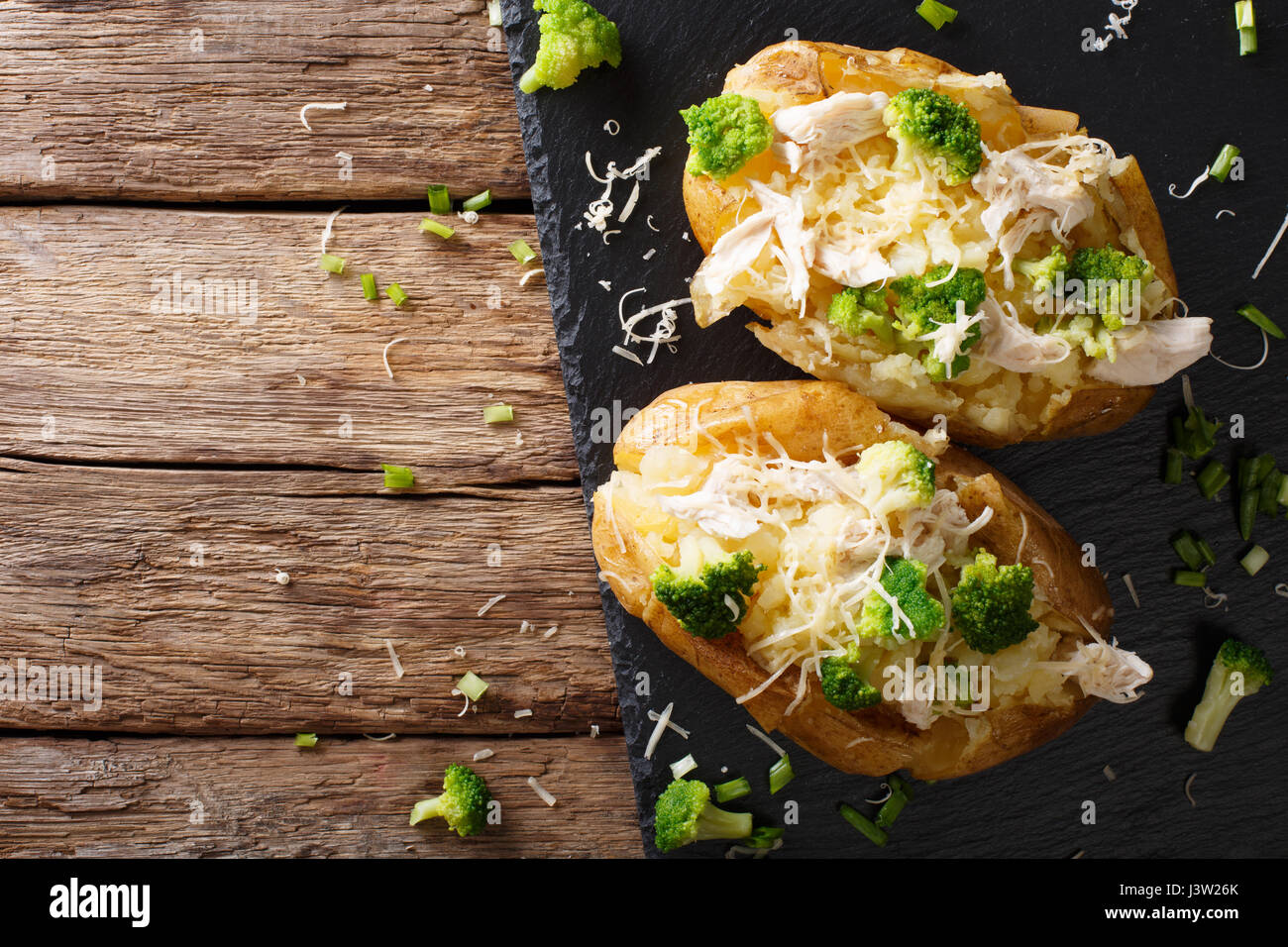 Abbondante acqua calda di patate al forno con broccoli, pollo, cipolla e formaggio vicino sul tavolo. vista orizzontale dal di sopra Foto Stock