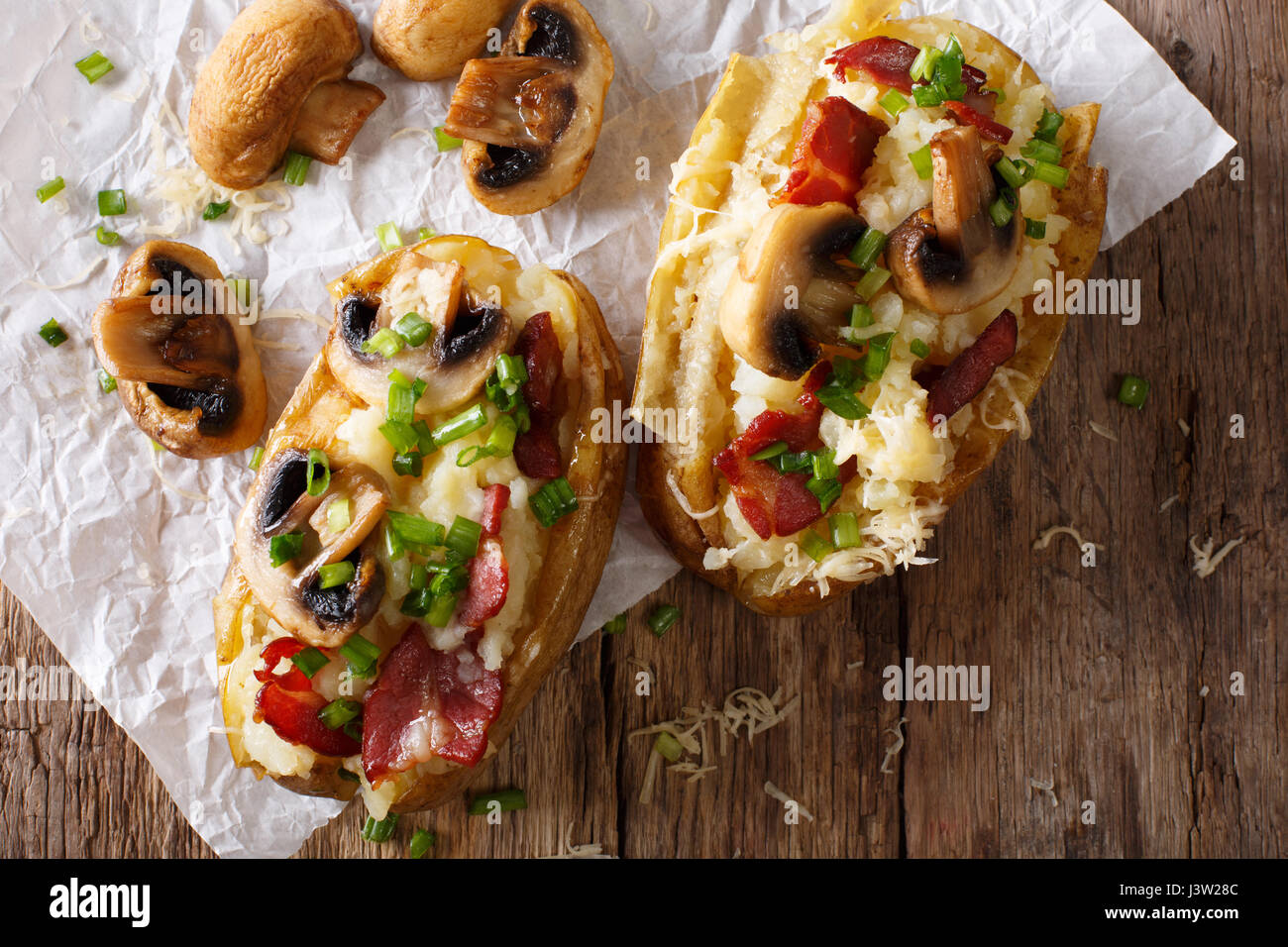 Patate al forno con pancetta, funghi e formaggio macro sul tavolo. vista orizzontale dal di sopra Foto Stock