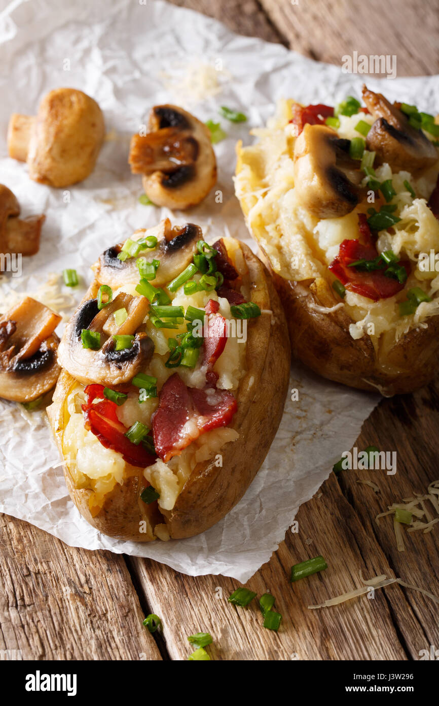 Deliziose patate al forno con pancetta, funghi e formaggio vicino sul piano verticale. Foto Stock