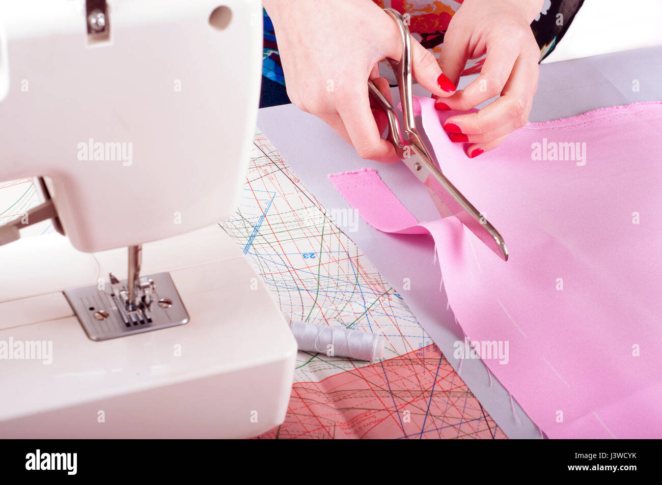 Designer di moda concetto. Womans mani di taglio tessuto rosa in studio. Sfondo del modello Foto Stock