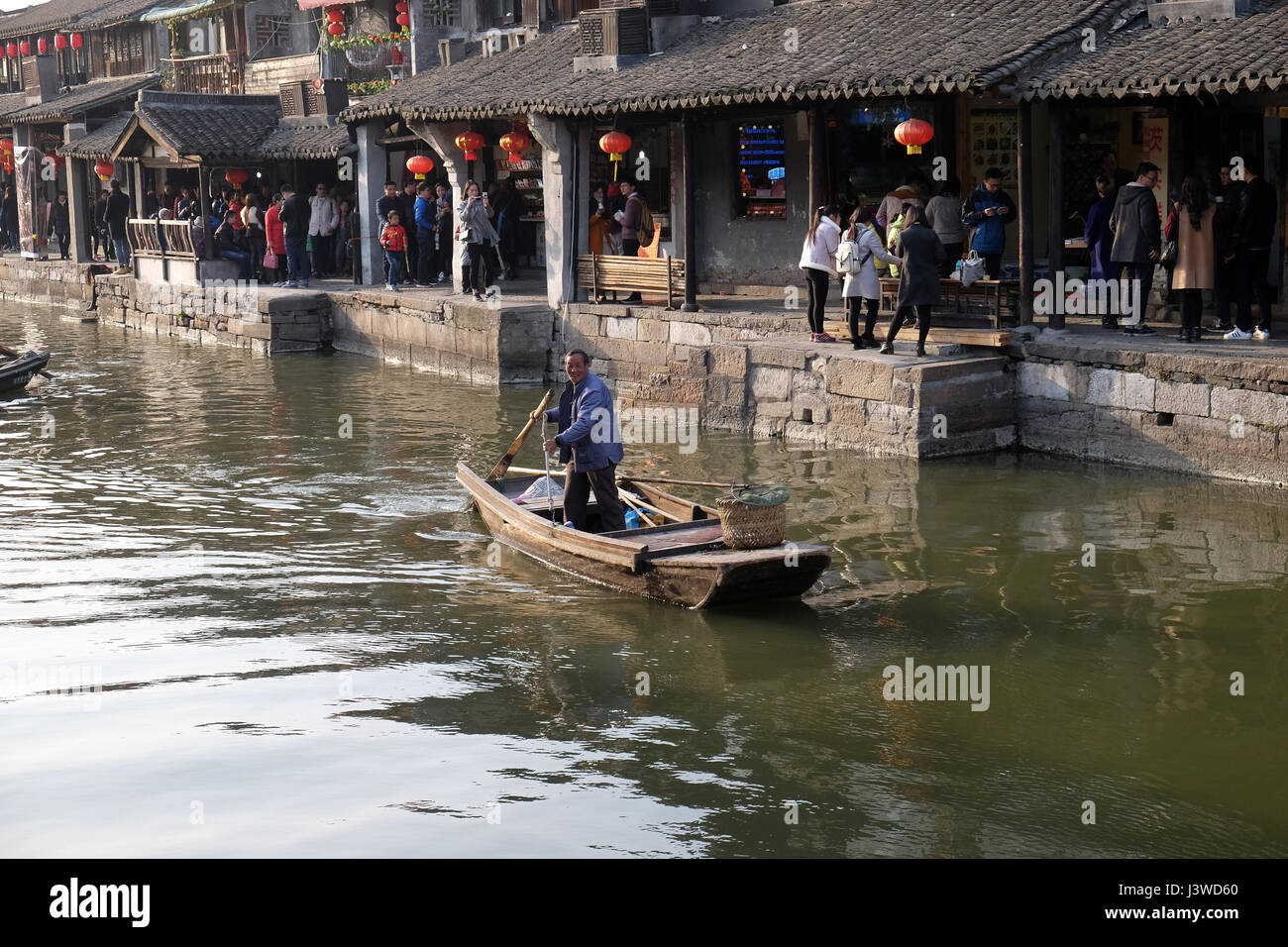 Uomo in un antica barca di legno sui canali di acqua di Xitang cittadina in provincia di Zhejiang, Cina, febbraio 20, 2016. Foto Stock