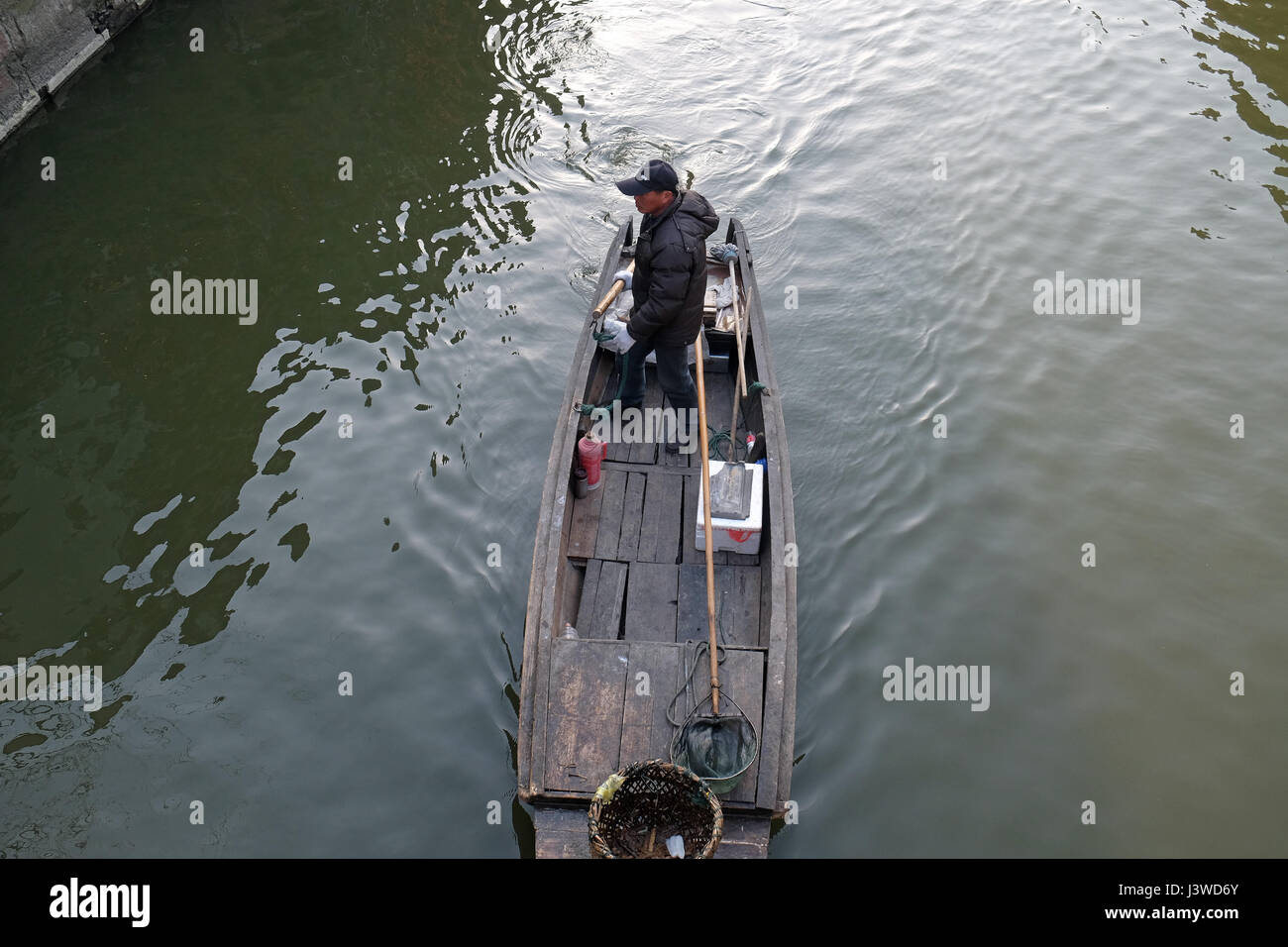 Uomo in un antica barca di legno sui canali di acqua di Xitang cittadina in provincia di Zhejiang, Cina, febbraio 20, 2016. Foto Stock