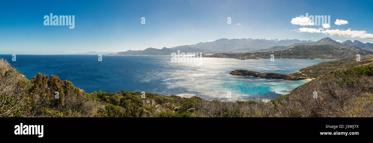 Vista panoramica attraverso la macchia della Revellata e Punta di l'Oscelluccia verso la cittadella di Calvi lungo la costa occidentale della Corsica con montagne innevate Foto Stock