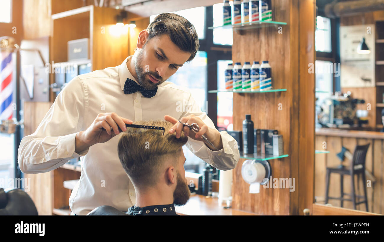 Giovane uomo in Barberia per la cura dei capelli il concetto di servizio Foto Stock