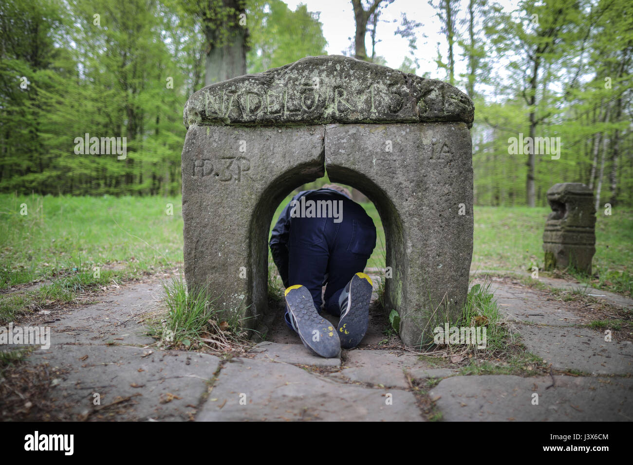 Friedewald, Germania. 8 Maggio, 2017. dpatop - un uomo si accovaccia bassa al fine di passare attraverso la cruna di un ago", una piccola porta di pietra del XVII secolo, in Friedewald, Germania, 8 maggio 2017. Secondo i costumi tradizionali, colui che passa attraverso il cancello si godono di salute in abbondanza. Foto: Frank Rumpenhorst/dpa/Alamy Live News Foto Stock