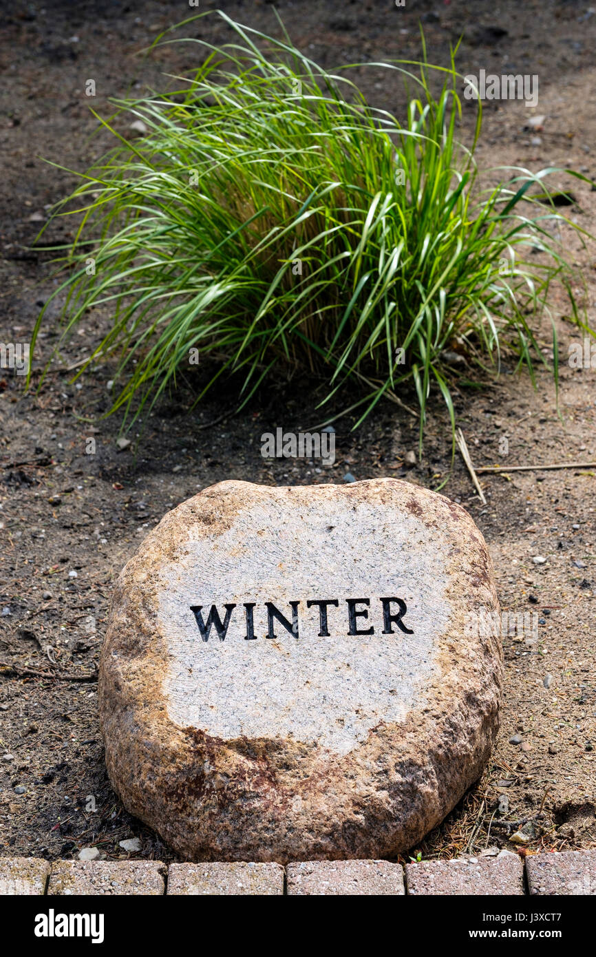 La parola scritta in inverno, incise in rilievo su un giardino decorativo pietra, stagioni dell'anno, decorazione, giardino di pietra, pietra ornamentale, segno d'inverno. Foto Stock