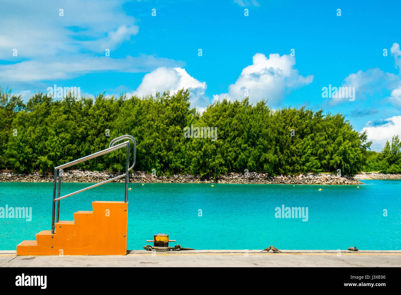 Tropical Island Jetty con orange scaletta e acquamarina mare sullo sfondo Foto Stock