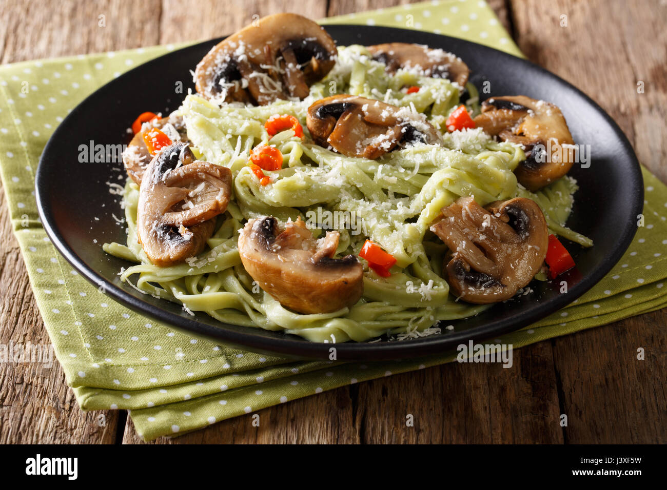 Gli spinaci fatti in casa Pasta con funghi fritti, peperoncino e formaggio close-up su una piastra orizzontale. Foto Stock