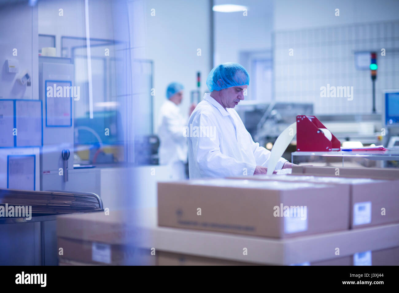 Lavoratori il confezionamento di prodotti farmaceutici sulla linea di produzione in stabilimento farmaceutico Foto Stock