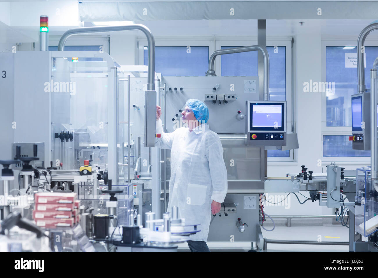 Lavoratore funzionamento di macchinari in stabilimento farmaceutico Foto Stock