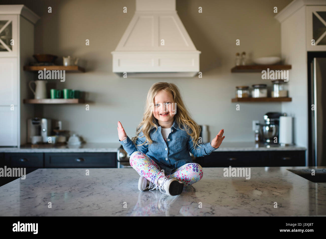 Ritratto di ragazza seduta zampe trasversale sul banco di cucina Foto Stock