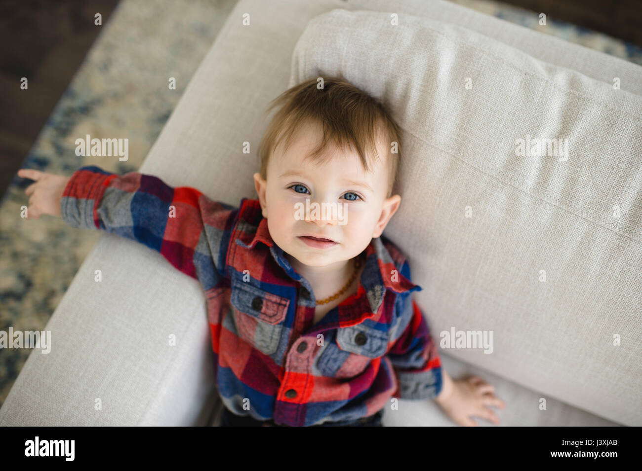 Ritratto di bimbi maschio sdraiata su un divano guardando in alto Foto Stock