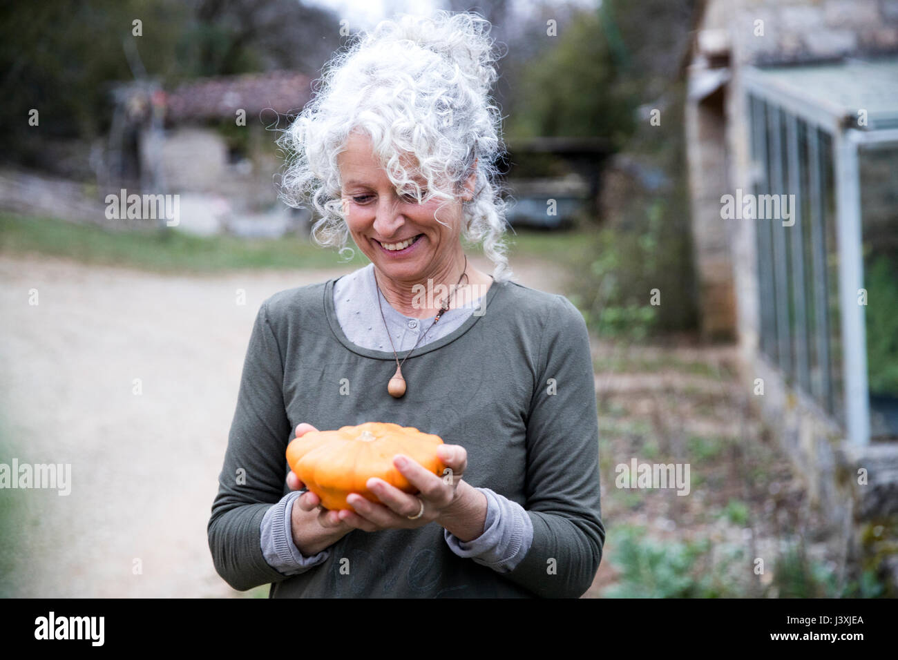 Femmina matura giardiniere holding squash vegetale in giardino Foto Stock