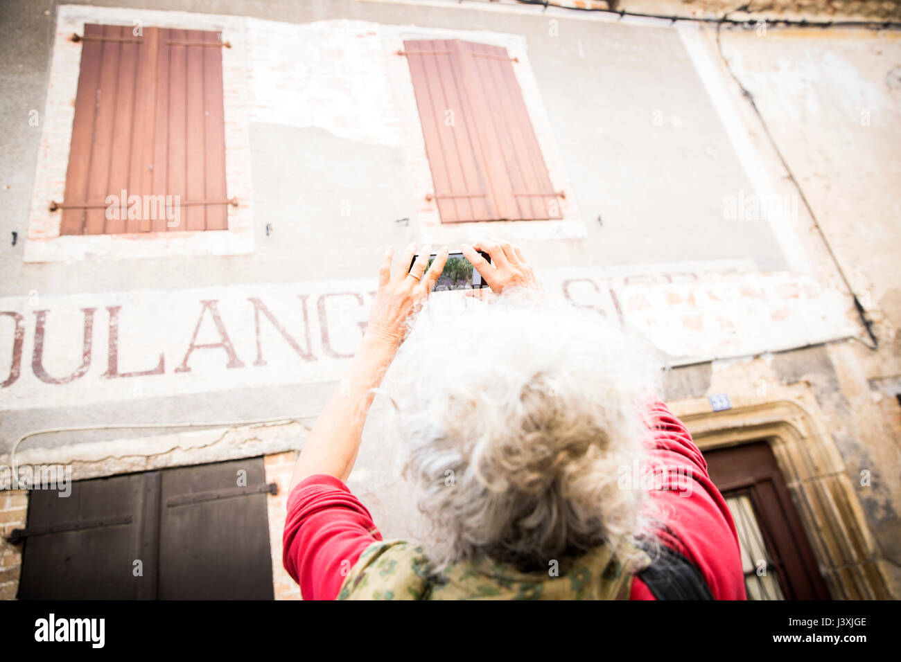 Donna prendendo fotografia di insegne su esterno dell'edificio, Bruniquel, Francia Foto Stock