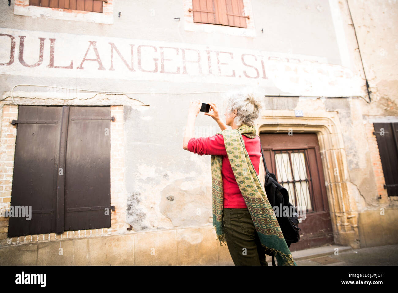 Donna prendendo fotografia di insegne su esterno dell'edificio, Bruniquel, Francia Foto Stock