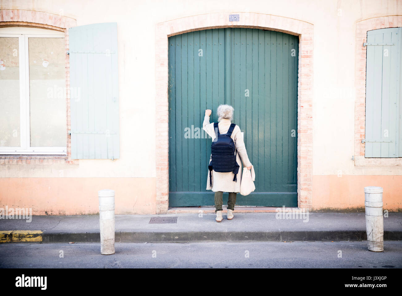 Vista posteriore della donna a bussare alla porta, Bruniquel, Francia Foto Stock